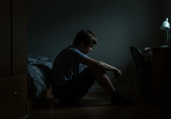 Teenager sitting alone, looking withdrawn and distant